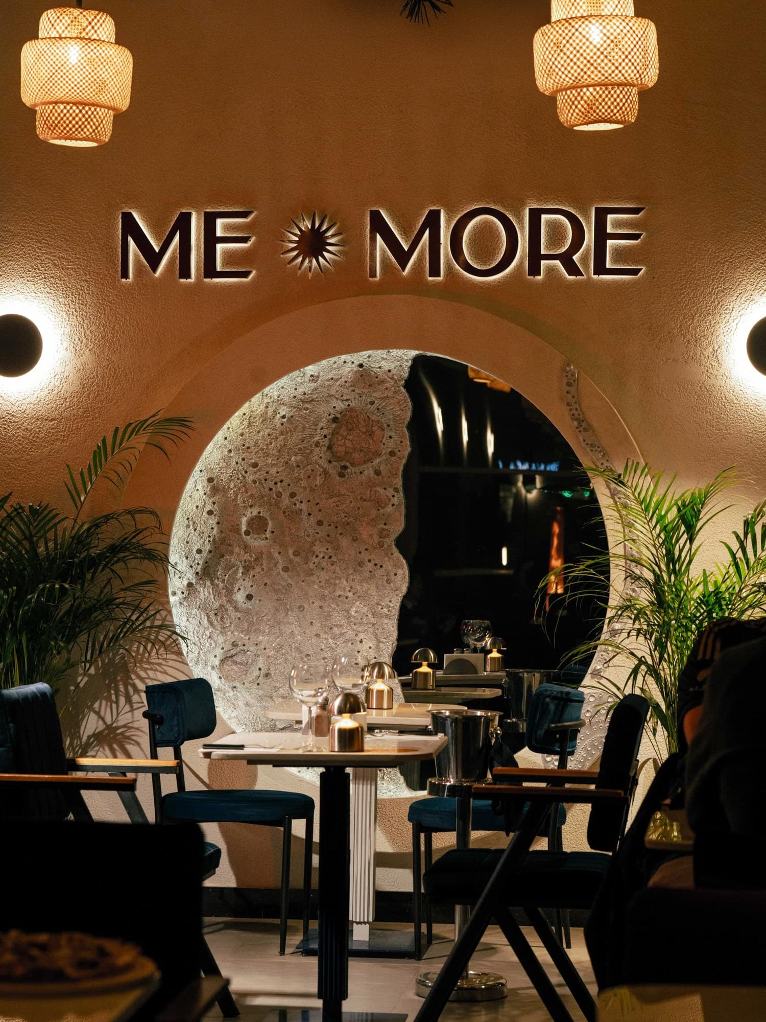 Me More Social salonu: ay duvarı, ME MORE tabelası ve masalar